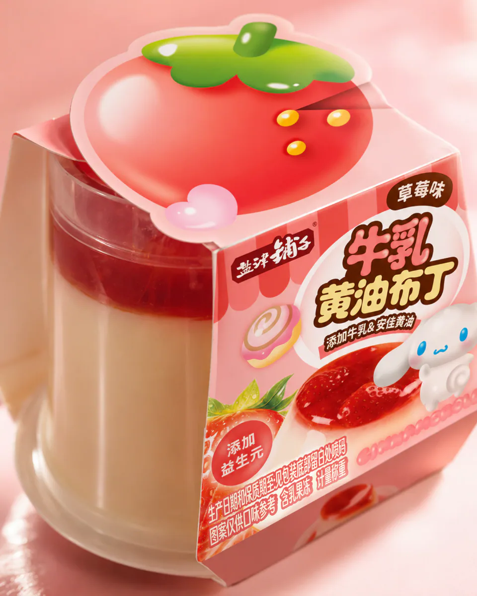 粉色背景中展示草莓味透明杯黄油布丁的包装纸套与大草莓顶部结构