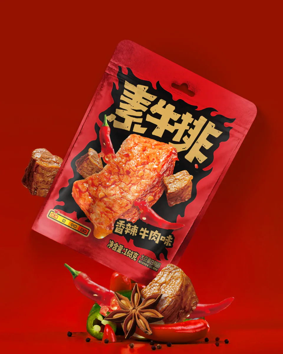 红色背景中倾斜陈列的素牛肉香辣牛肉味包装与辣椒、香料