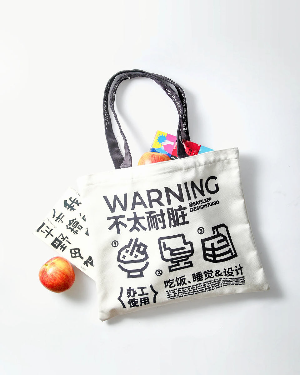 浅色场景中完整展示的WARNING帆布袋、苹果及卡片