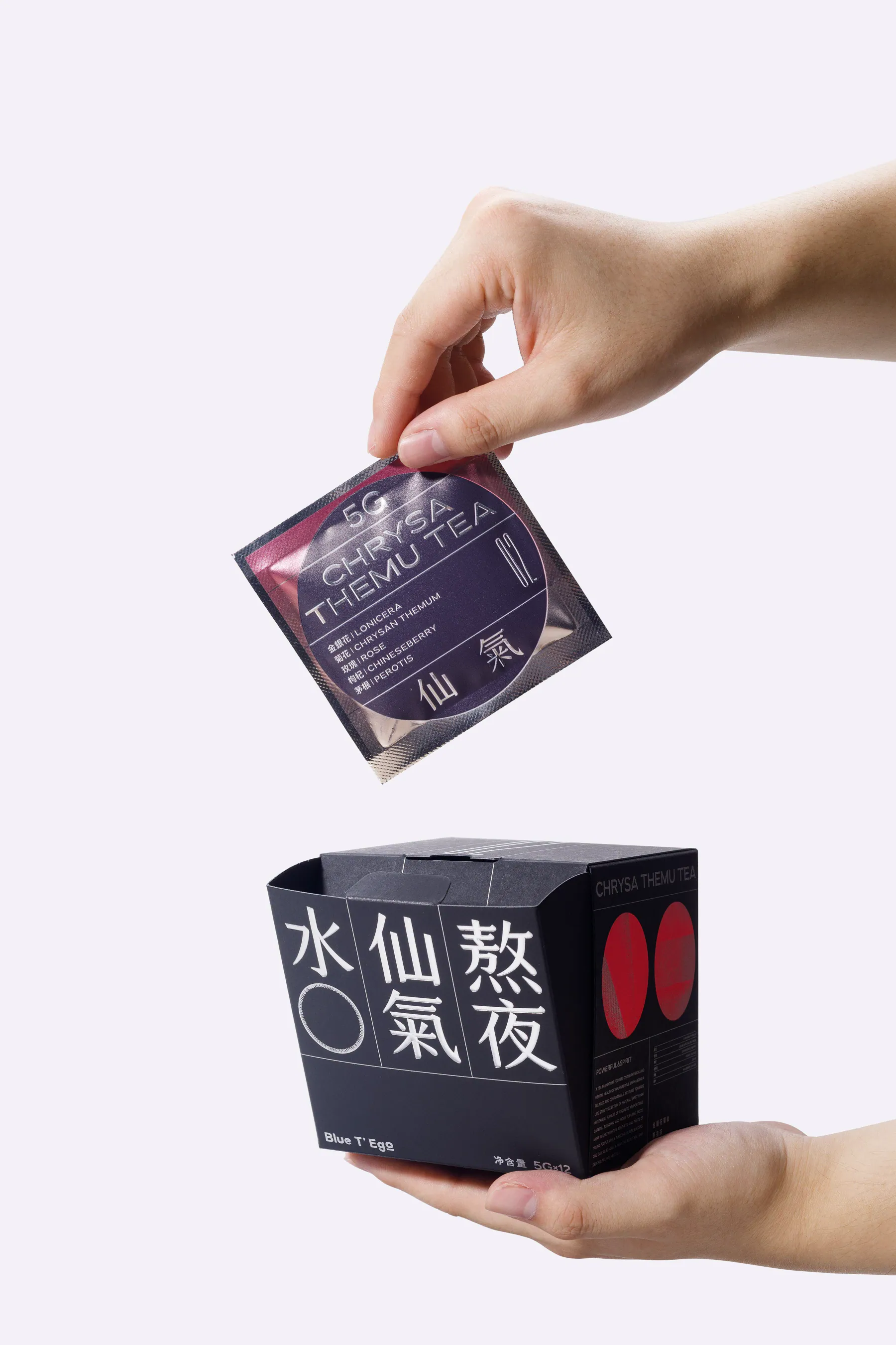 手持 Blue T’Ego 茶包与黑色袋泡茶盒装的画面
