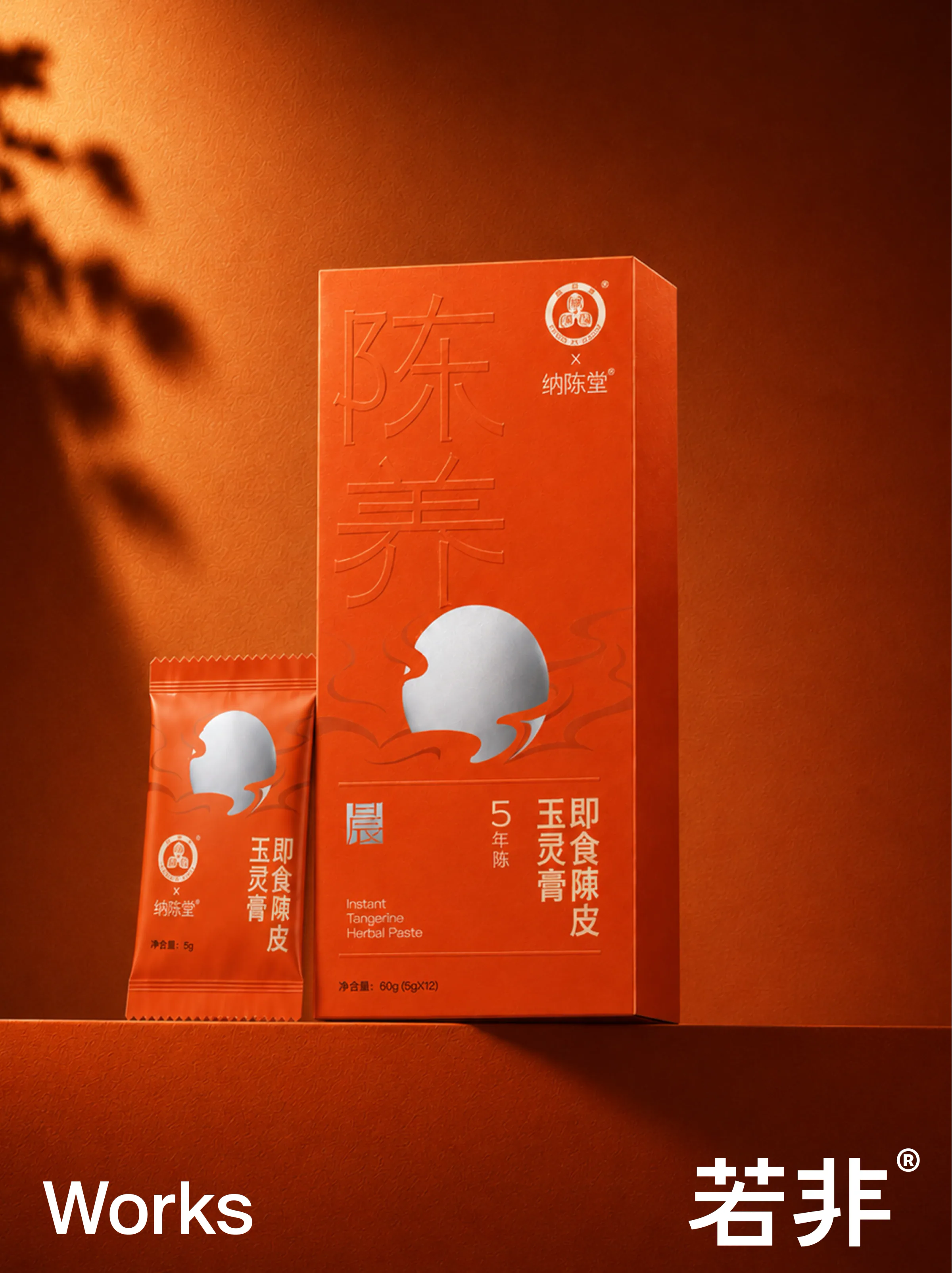 暖棕橙色背景中的玉灵膏陈皮膏礼盒与单条装,盒面为银色晨日图形