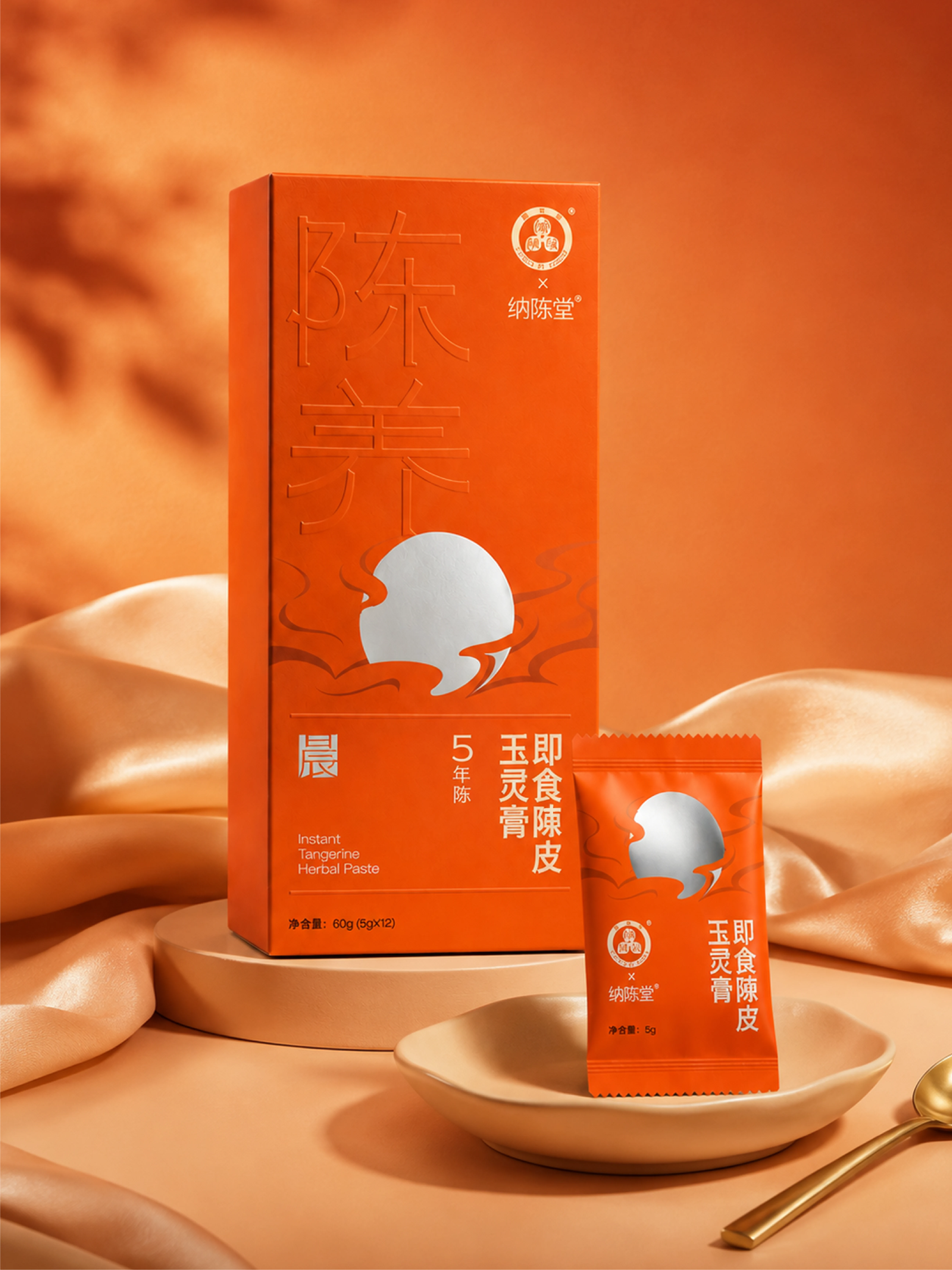 橙色丝绸与瓷盘场景中的玉灵膏陈皮膏礼盒和单条装