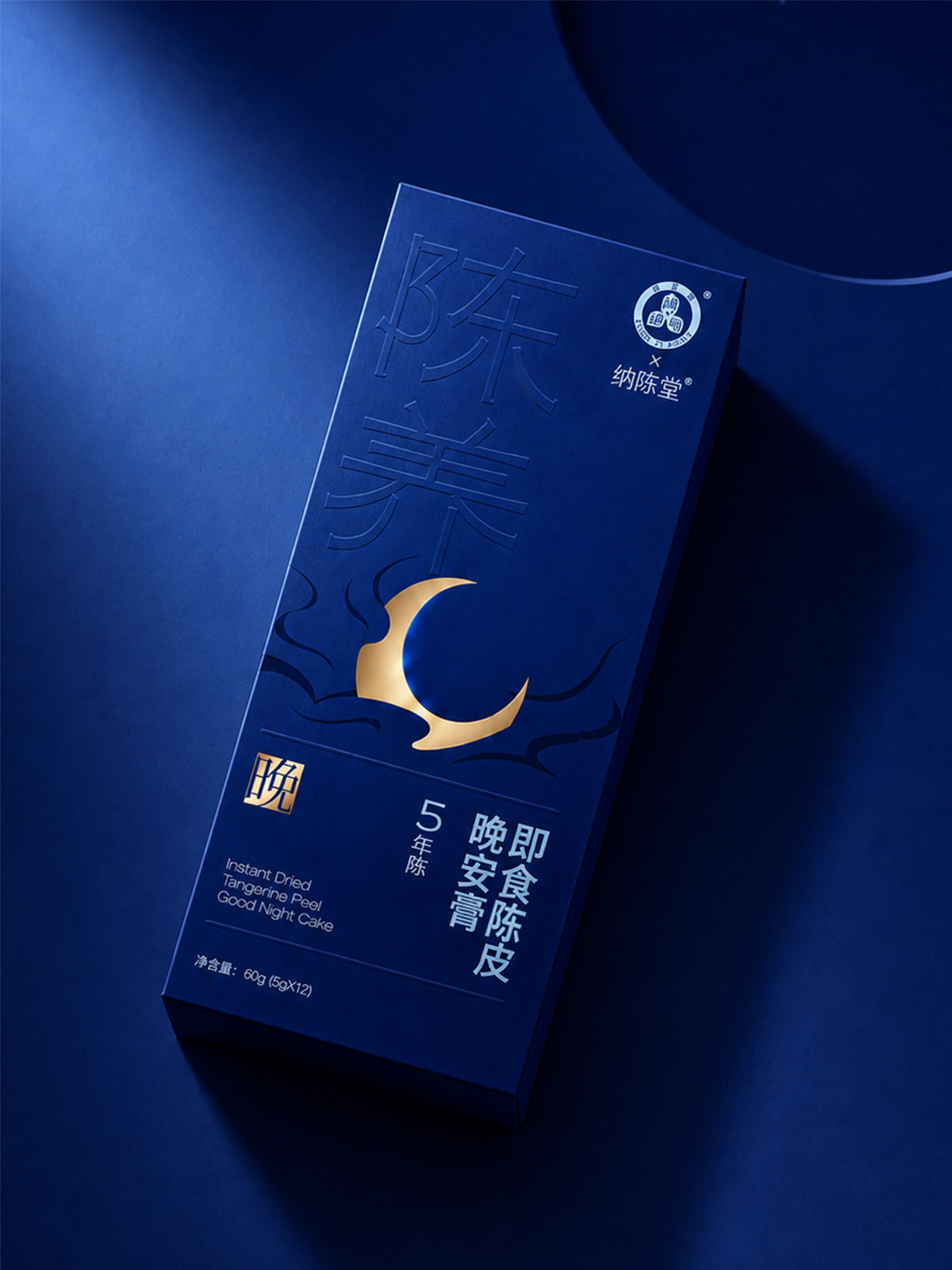 蓝色背景中倾斜摆放的晚安膏陈皮膏礼盒,盒面有金色月牙图形