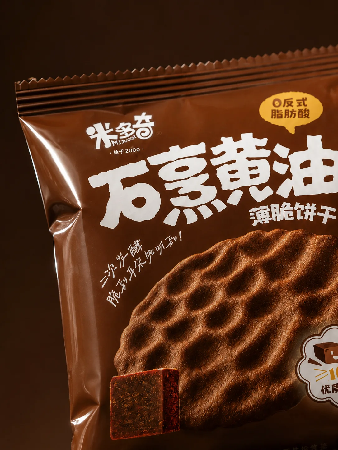 深棕背景中米多奇石烹红糖薄脆饼干包装局部与饼干特写