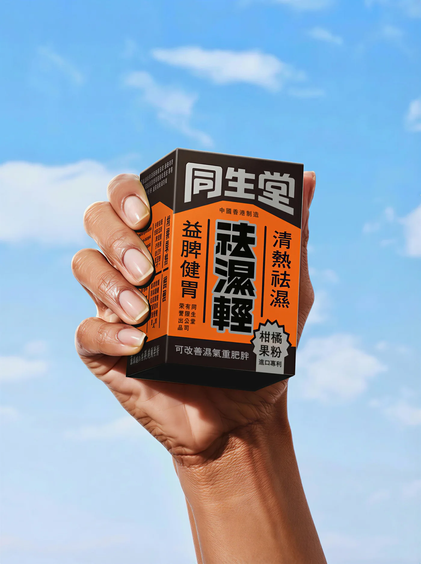 蓝天背景前手持的同生堂祛湿轻橙黑色盒装